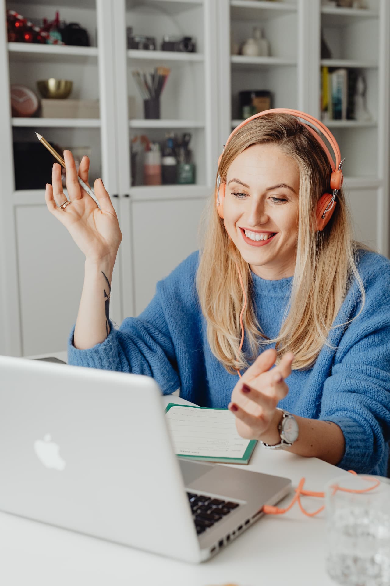 A joyful coaching session online — smiling woman with headphones at her laptop, gesturing mid-conversation